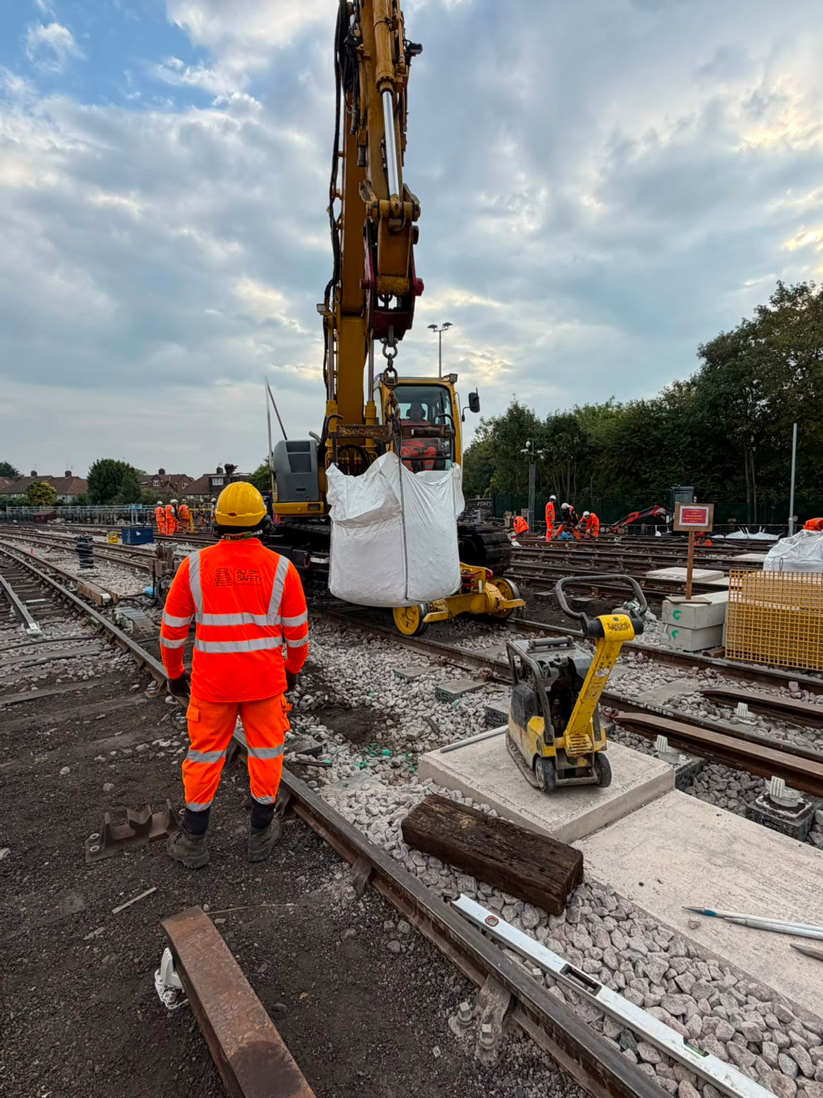 Operator at the controls of a yellow road-rail excavator on a railway worksite