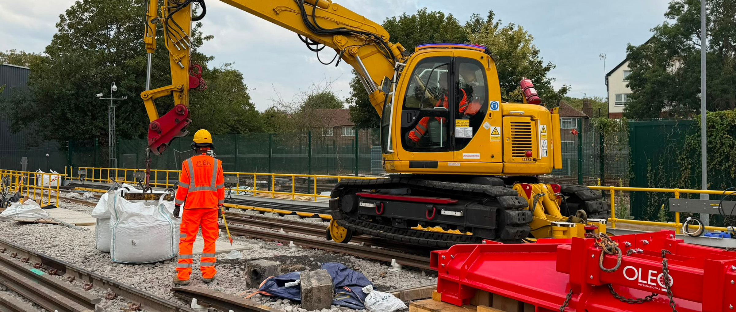 AJ personnel and a yellow tracked excavator on a railway worksite