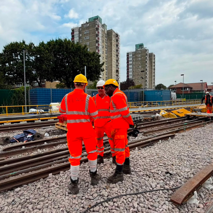 AJ rail workers together beside a track renewal worksite