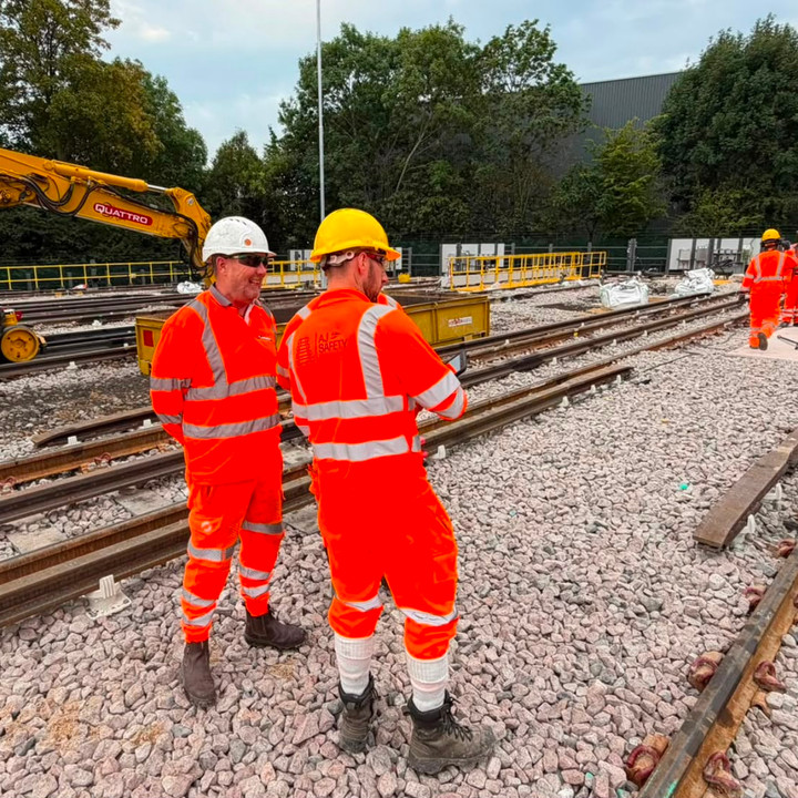 Rail personnel working among tracks, equipment and yellow rail plant
