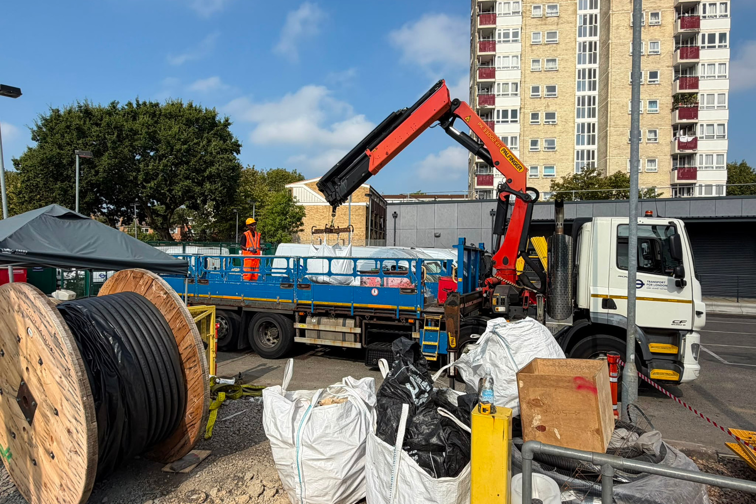 Vehicle-mounted crane and AJ worker preparing a lifting activity in a works yard