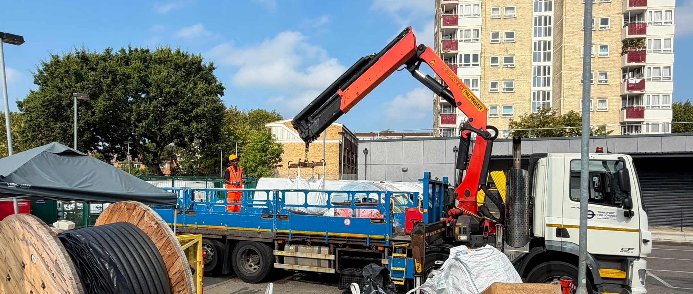 AJ lifting personnel beside a vehicle-mounted crane and load in a works compound