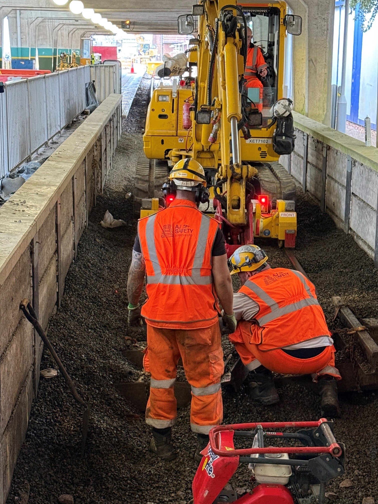 Machine Controller coordinating personnel beside rail plant on a London Underground worksite