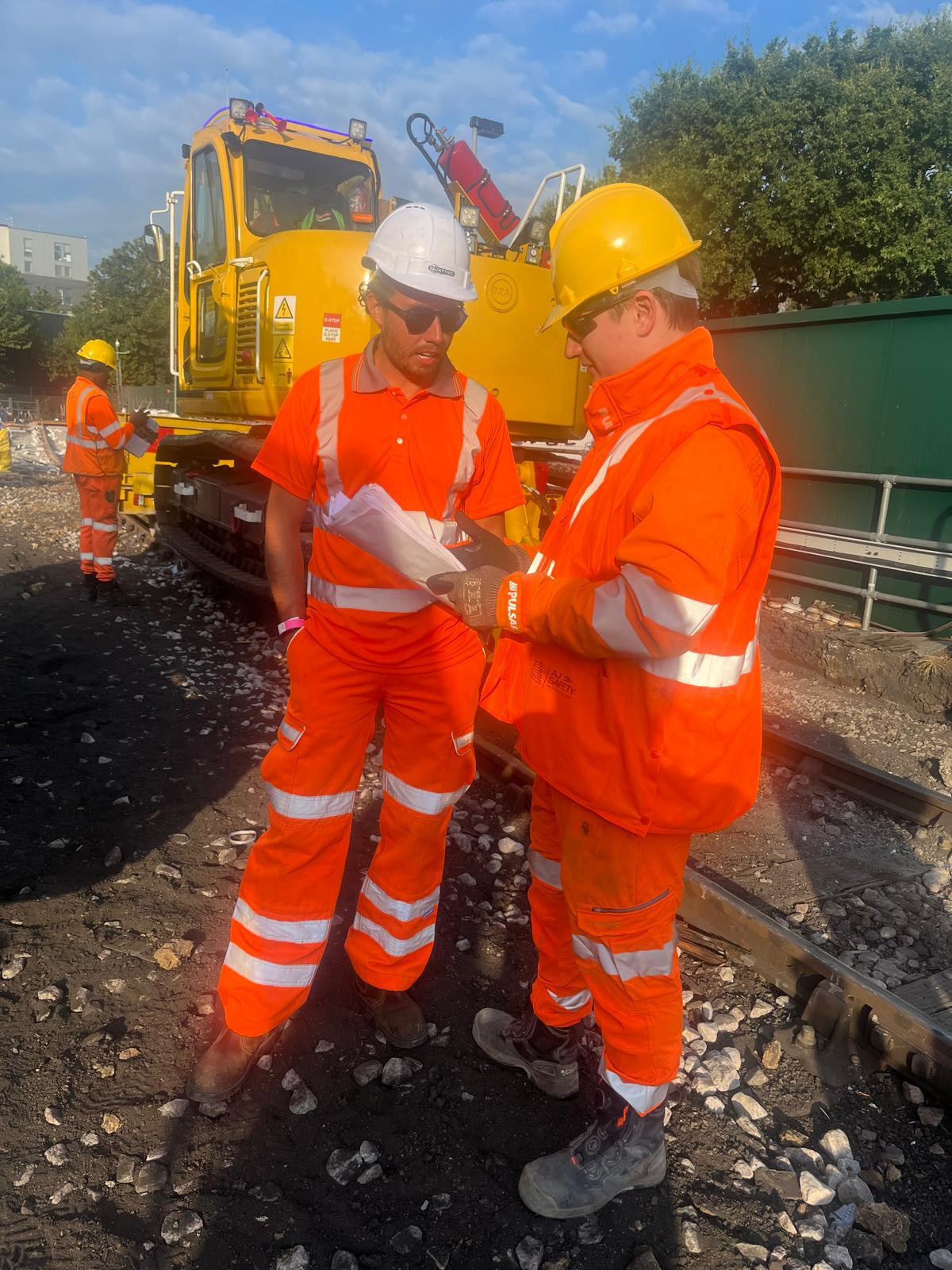 Rail colleagues reviewing work information beside active plant