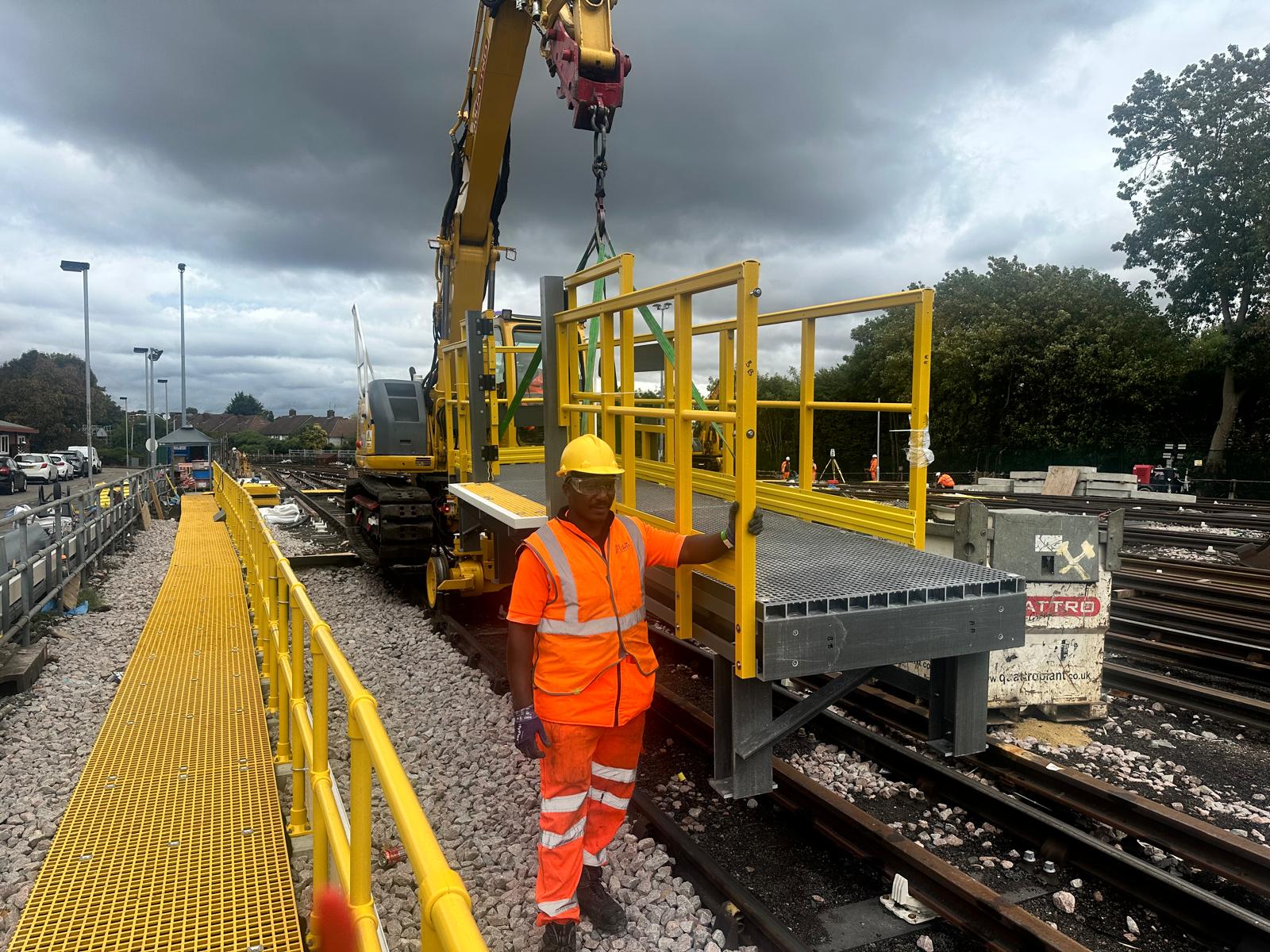 Rail worker beside yellow lifting plant and an access platform