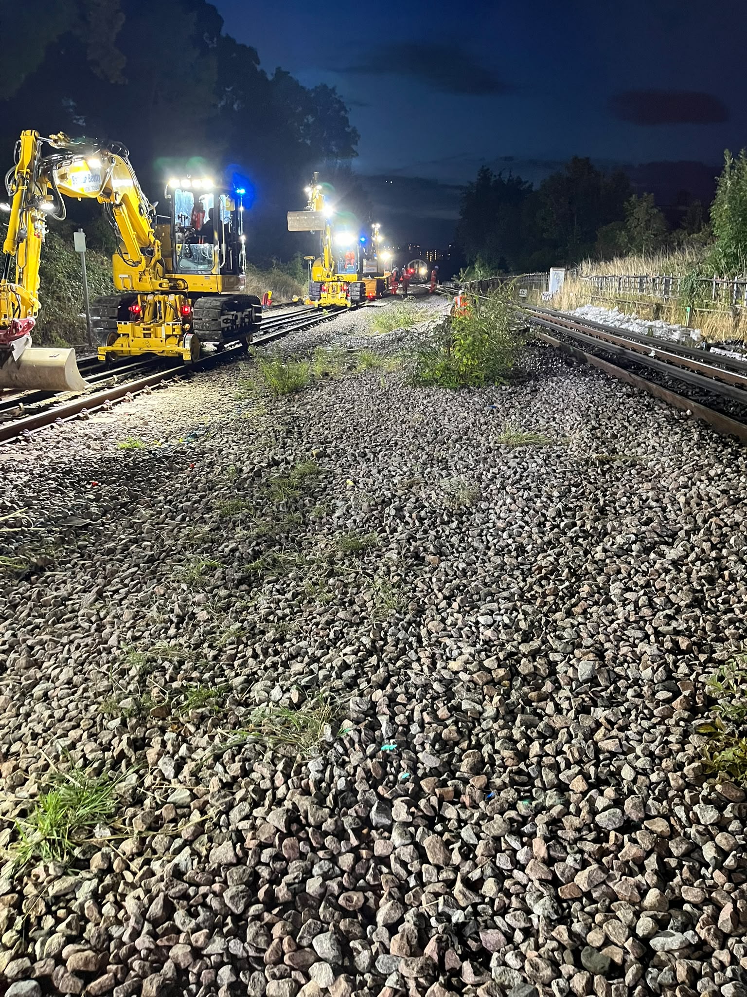 Yellow rail plant and track personnel during night engineering work